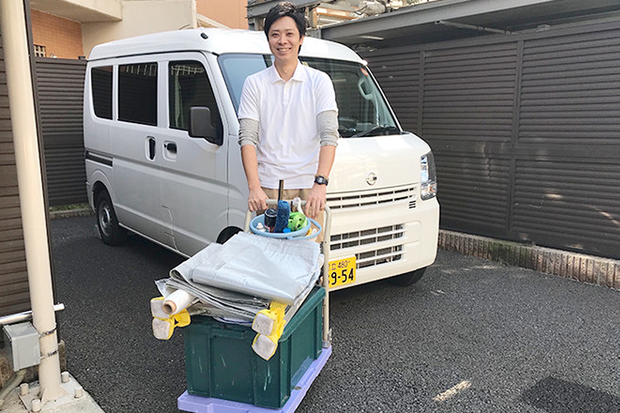 笑顔で道具を乗せた台車を押すプロ