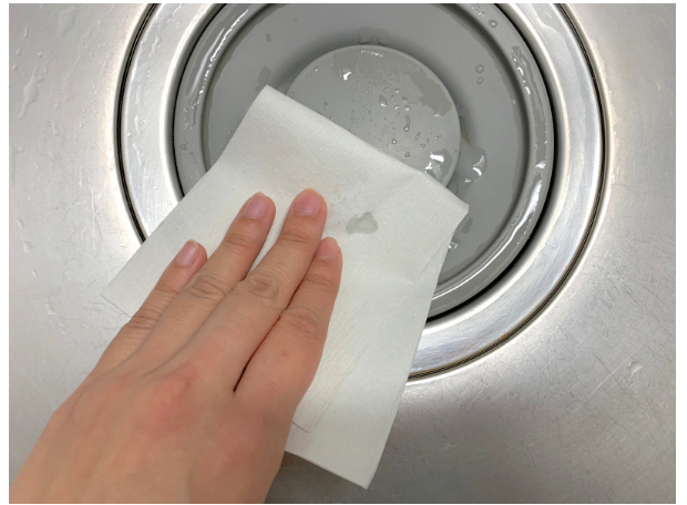 キッチンペーパーでシンクの水を拭き取る