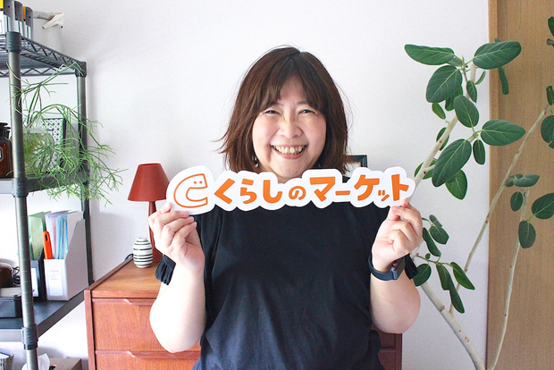 笑顔でくらしのマーケットのパネルを持つ内山さん