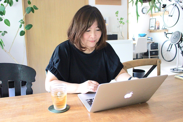 自宅のテーブルでパソコンを操作する内山さん