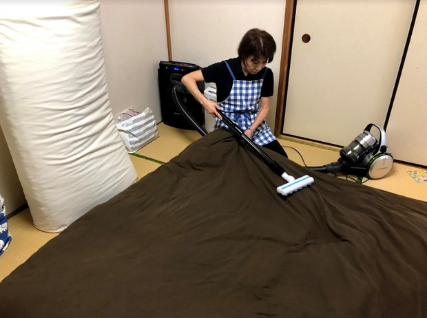 布団に掃除機をかける女性