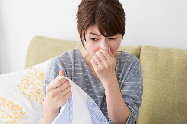 洗濯物に鼻をつまむ女性