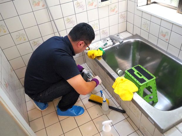 浴室の排水口を掃除している