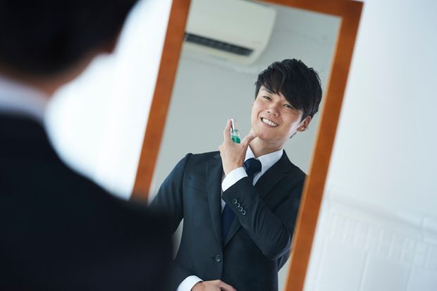 襟元にスプレーをかける男性