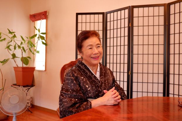 部屋の中で座っている着物を着た笑顔の女性