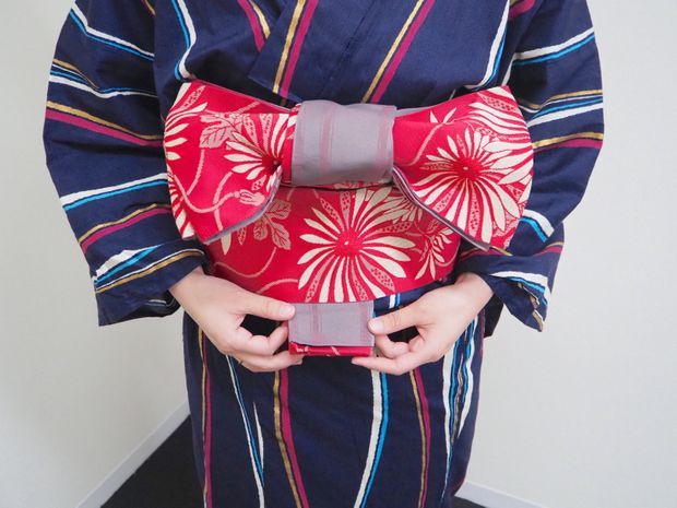 帯の下に出てきた手先を帯の内側に入れる女性