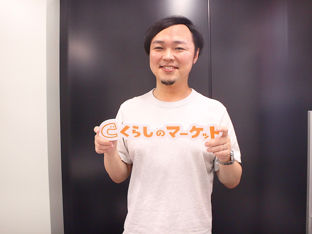 くらしのマーケットのロゴを持って笑う三瓶さん